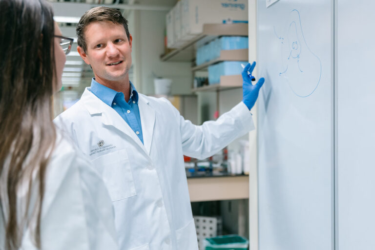 Scientist explaining a topic to a colleague at a white board